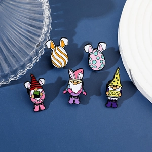 Détail de cinq broches émaillées de gnomes de Noël et d'œufs sur un fond bleu profond