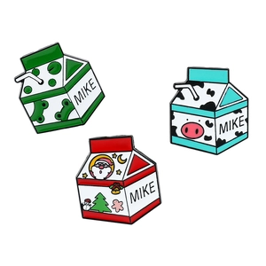 Trois pin's émaillés en forme de brique de lait avec motifs grenouille, vache et Noël