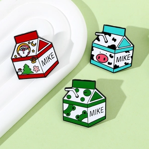 Détail de trois épingles en émail colorées en forme de briques de lait aux motifs mignons