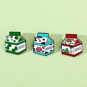 Détail de trois épingles en émail en forme de brique de lait avec grenouille et Noël