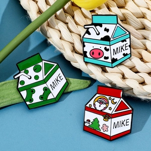 Vue détaillée de trois broches en émail en forme de briques de lait avec grenouille et Noël