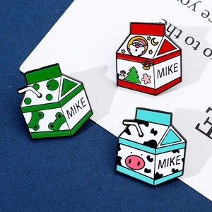 Détail de broches en émail en forme de brique de lait avec motifs Père Noël et grenouille