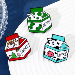 Détail de broches en émail boîte de lait avec motifs grenouille et Père Noël sur plateau