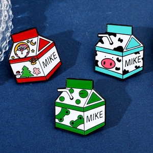 Gros plan de broches brique de lait en émail avec motifs de Noël, de vache et de grenouille