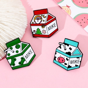Vue détaillée de trois broches en émail en forme de briques de lait avec grenouille et Noël