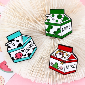 Détail de trois épingles en émail en forme de brique de lait avec motif Père Noël