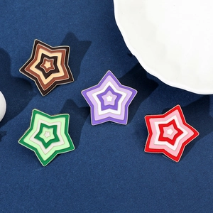 Detailed view of colorful gradient star brooches with enamel finish on blue fabric