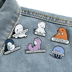 Cartoon ocean animal enamel pin set on blue denim jacket featuring whale and penguin