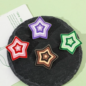 Detail of colorful gradient star enamel brooches with gold metal edges on a black plate
