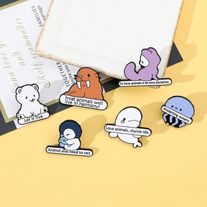 Close-up of enamel ocean animal pins with eco-friendly slogans on a textured tray