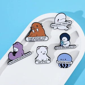Detail of 6 ocean-themed enamel pins with environmental slogans on white tray