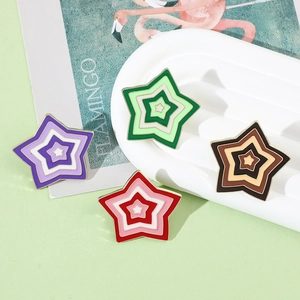 Detail of colorful enamel star brooches in purple green and red on elegant display tray