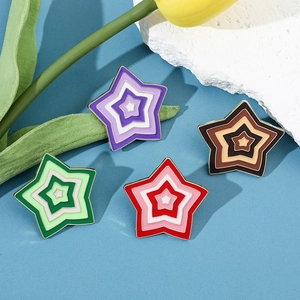 Macro shot of colorful star-shaped enamel pins in purple, green, red, and brown tones