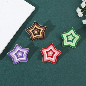 Detail of colorful gradient star brooches in brown, green, purple and red enamel finish