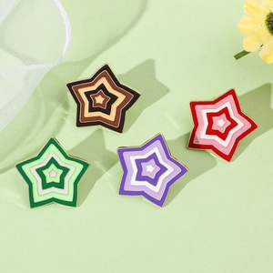 Flat lay of colorful star enamel pins set in gradient shades on a soft green background