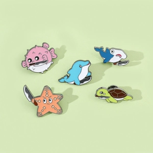 Macro detail of five creative ocean animal enamel pins with humorous knife-holding designs