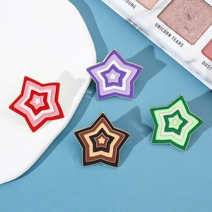 Detail view of four colorful star-shaped enamel brooches with gold-plated metal borders