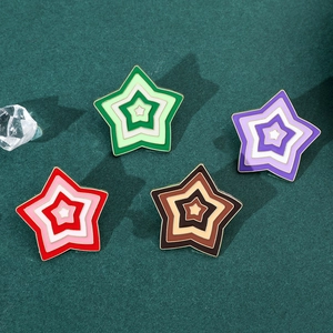 Detailed view of colorful gradient star enamel pins on a green textured felt background