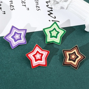 Detailed view of four colorful star-shaped enamel pins with gold trim on dark background