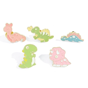 Dettaglio di cinque simpatiche spille a forma di dinosauro colorate con bordi dorati