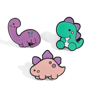 Dettaglio di un set di tre spillette in smalto colorato a forma di piccoli dinosauri