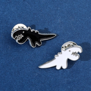 Dettaglio di spillette smaltate a dinosauro bianco e nero con chiusura a farfalla in metallo