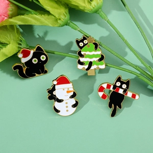 Close-up of four cute black cat enamel pins with Christmas hats, trees, and snowmen