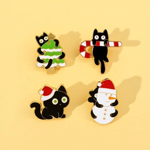 Detailed view of four black Christmas cat enamel pins on warm yellow backdrop