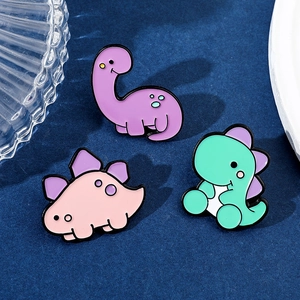 Tre simpatiche spille in smalto a forma di dinosauro color pastello su fondo blu