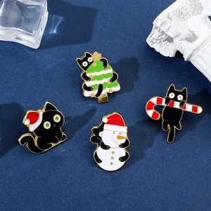 Detail of cartoon Christmas black cat enamel pins featuring holiday trees and snowmen