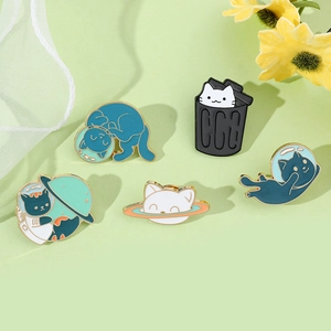 Macro detail of five cute space cat enamel pins with planet motifs on a floral background