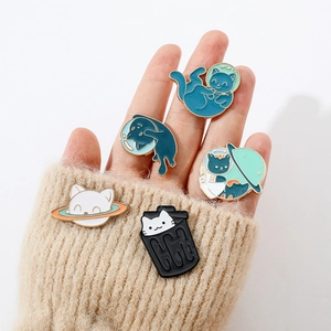 Detail of cute enamel cat pins pinned on beige knit sweater sleeve with hand holding