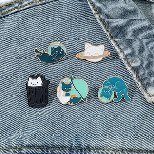 Set of five cute cartoon cat enamel pins displayed on a denim jacket pocket