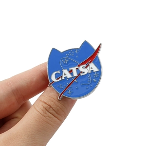 Close-up of CATSA enamel pin showing NASA parody logo with blue base and white stars