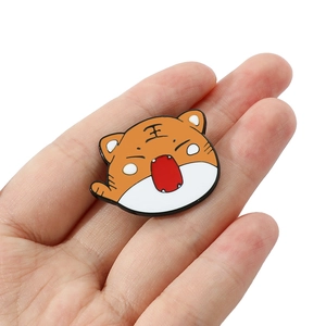 Detail of cute orange tiger enamel pin with traditional character shown in hand