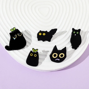 Detailed set of five creative black cat enamel pins displayed on a decorative white dish