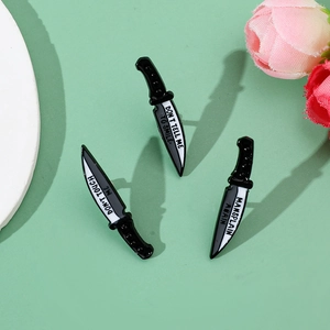 Detail of three dagger enamel pins with feminist slogans on a mint green backdrop
