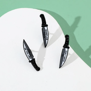 Detail of three dagger enamel pins with feminist slogans on a white round display