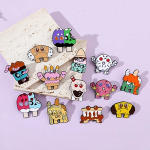 Detailed collection of colorful monster dessert enamel pins on a textured stone surface