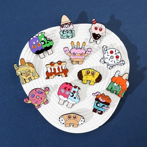 Collection of eleven cartoon monster enamel pins displayed on a white ceramic plate