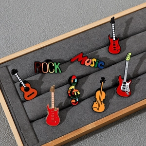 Vue détaillée de pins musicaux en émail avec guitares et violon dans un écrin à bijoux