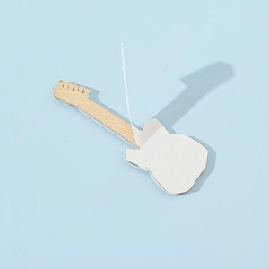 Macro view of guitar shaped metal accessory with golden finish and adhesive backing