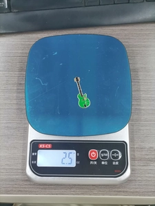 Green guitar enamel pin on a scale weighing 2.5g for DIY metal accessory detailing