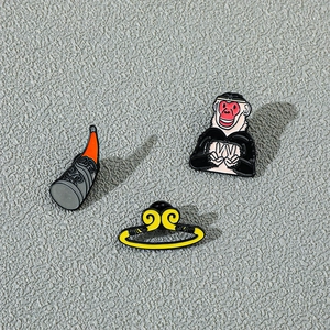 Detailed view of three enamel pins featuring Monkey King head, golden hoop, and staff