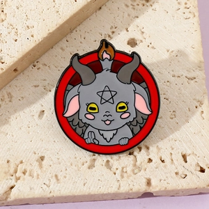 Detailed macro of a cartoon Baphomet enamel pin with red ring on stone texture