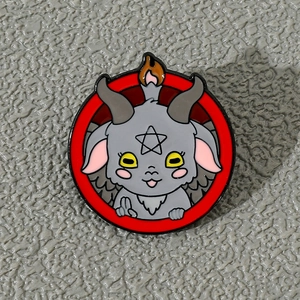 Macro detail of a cartoon devil sheep enamel pin with red ring and pentagram symbol