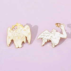 Macro detail of surrealist white enamel seraphim and crown brooches with gold plating