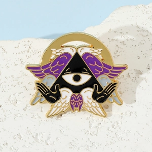 Macro shot of mystical enamel pin with Eye of Providence and purple angel wings on white lace