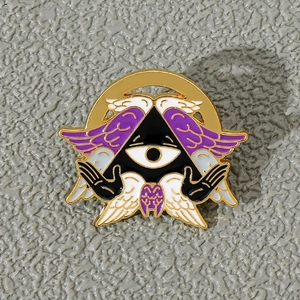 Close-up of enamel pin with single eye and wings on textured background
