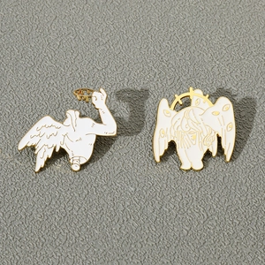 Detailed view of white enamel angel wing pins with gold plating and eye motifs
